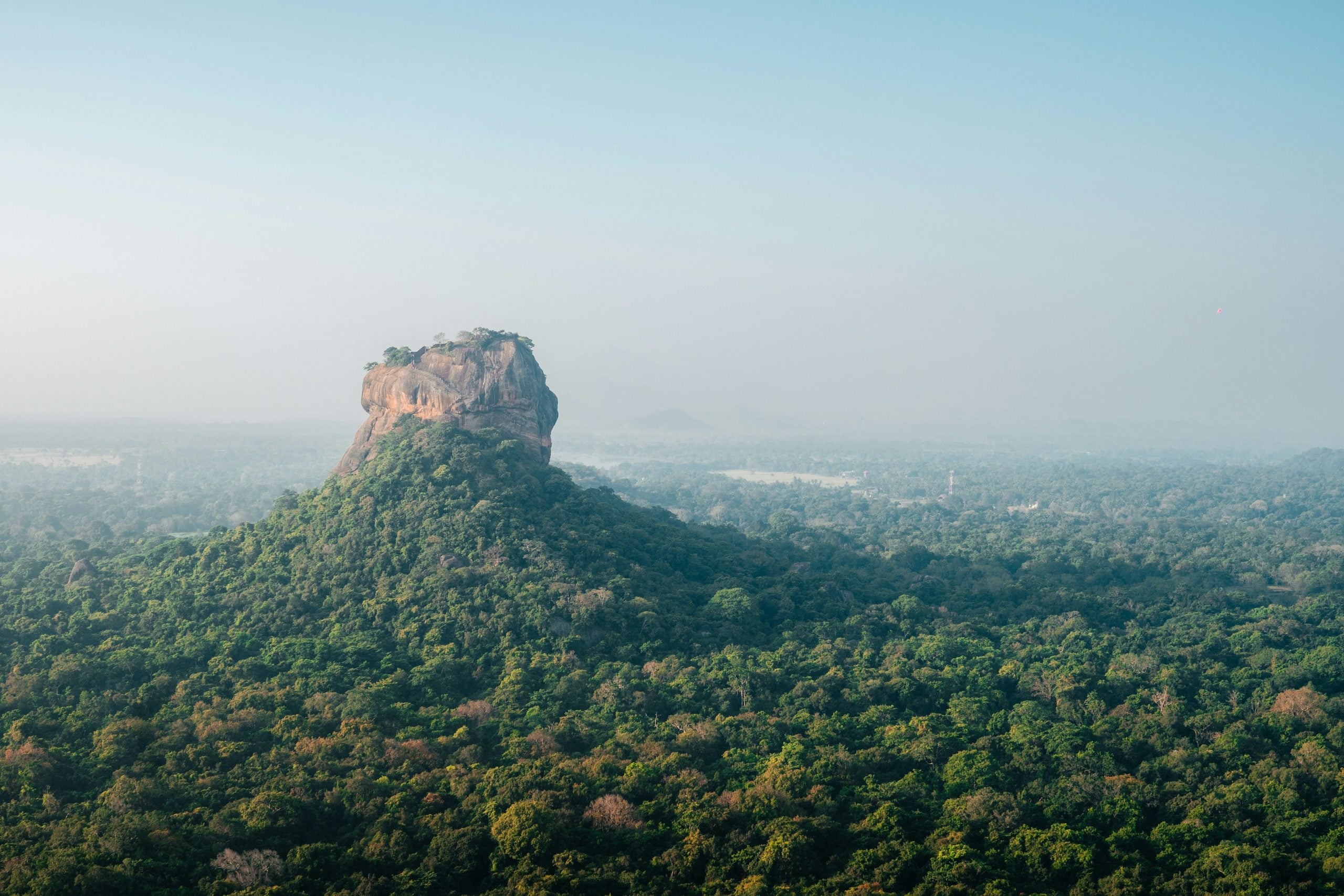 Sigiriya rock fortress rising above the forest in morning haze